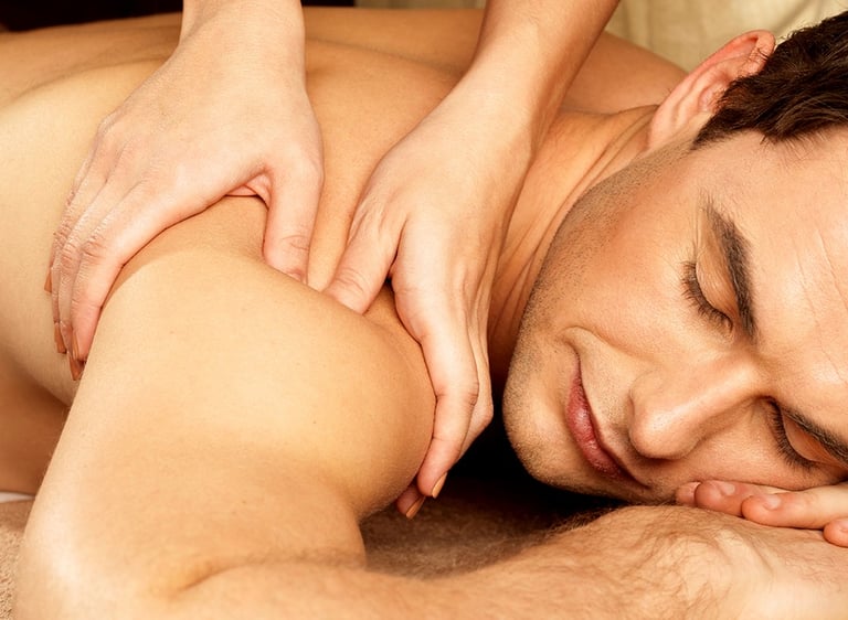 Female practitioner giving a deep tissue back massage to a male client in a wellness center