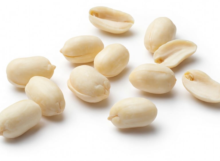 A collection of raw, blanched peanuts without shells scattered on a clean white background.
