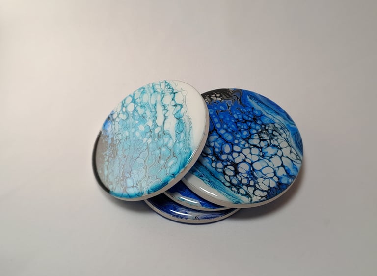 Handmade acrylic pour coasters with blue and white marble resin fluid art designs.