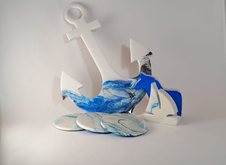 Nautical resin art set featuring a blue and white anchor, sailboat decor, and marbled coasters.