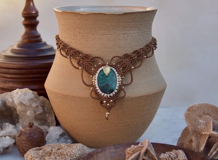Collar de macramé hecho a mano con piedra verde exhibido sobre jarrón de cerámica y cristales natura