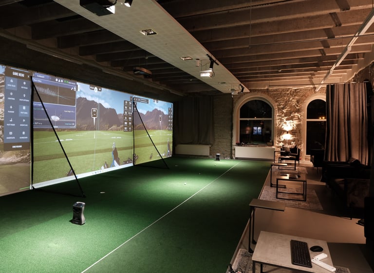 a man is playing golf in a room with a large screen