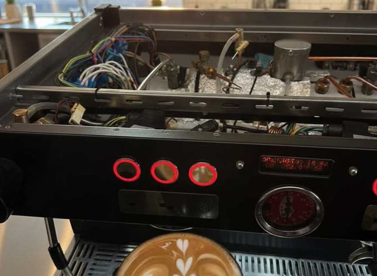 Specialized technician performing internal maintenance on a commercial espresso machine in a local c