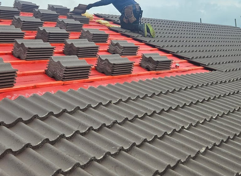 Professional roofer installing new concrete roof tiles on a residential house rooftop. in Essex