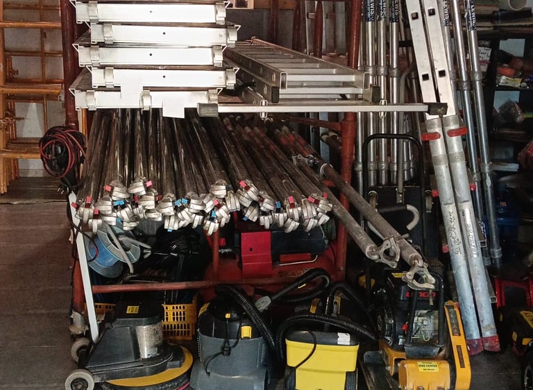 Professional scaffolding equipment, aluminum ladders, and industrial cleaning tools stored in a warehouse.