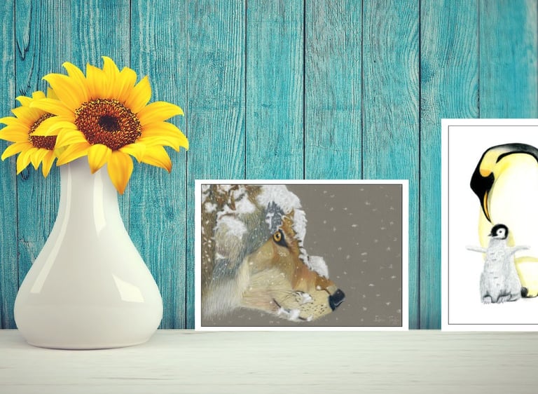 Wolf and penguin greeting cards on a shelf next to yellow sunflowers in a white vase.