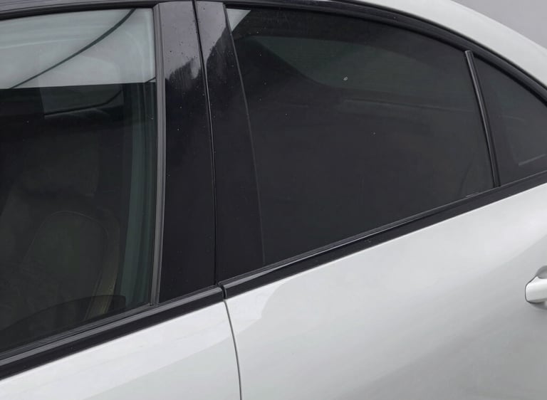 Close-up of a white car door window featuring visible scratches and marks on the tinted glass.