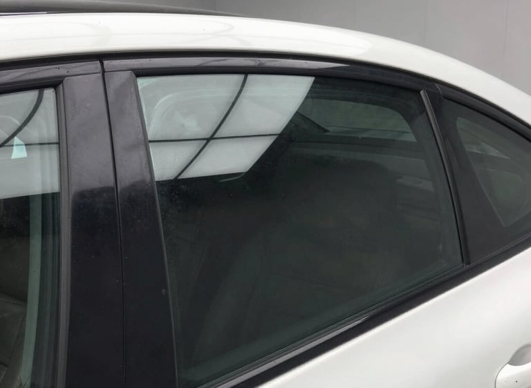 Close-up of a sleek car window with a subtle tint reflecting sunlight.