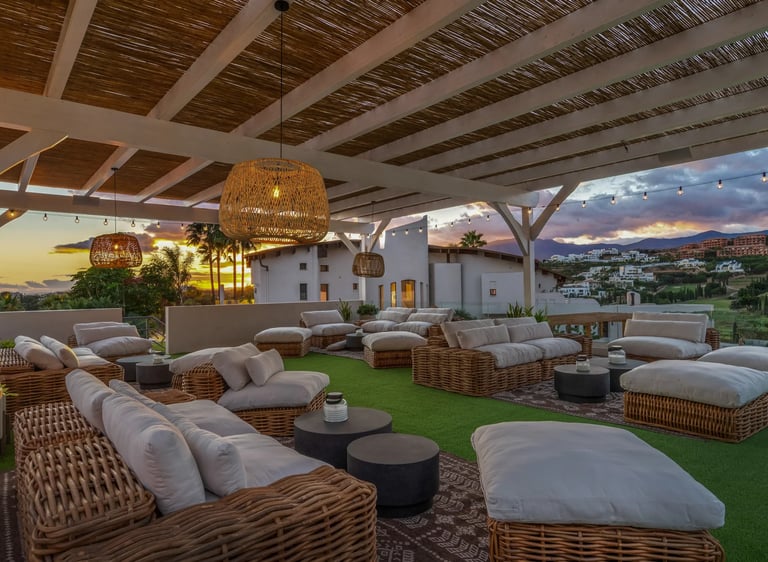 Covered rooftop lounge with rattan seating at sunset