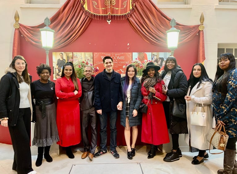 A diverse group of people standing together in front of a red theatrical backdrop and lanterns.