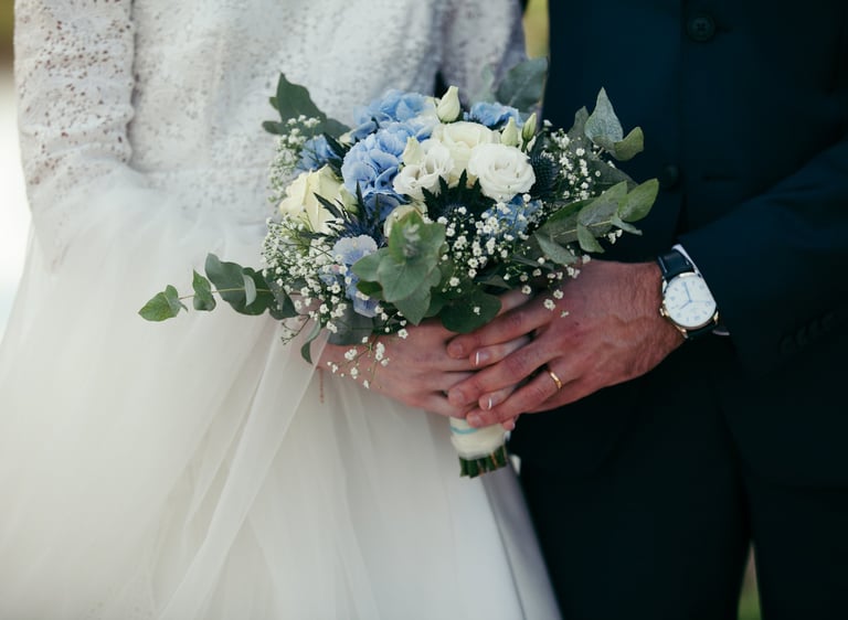 Des mariés en train de tenir le bouquet/a bride and groom holding a bouquet of flowers