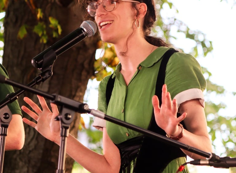 chanteuse interprétant une chanson folk sur scène /singer in a green dress singing into a microphone