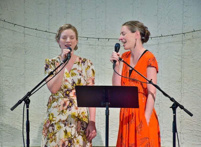 two women singing in front of microphones