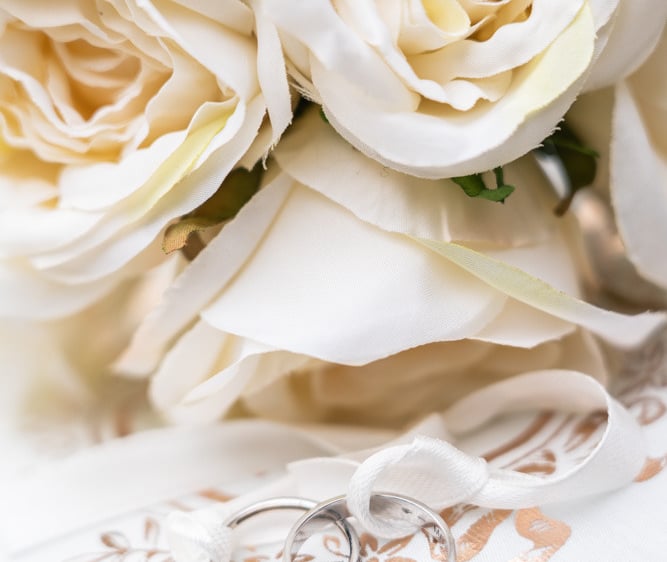a bouquet of white roses and wedding rings