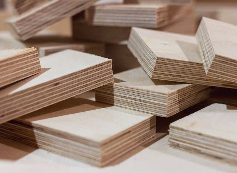 Stacks of cut birch plywood boards showing multi-layered wood grain for construction.