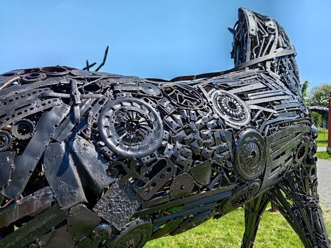 A detailed scrap metal sculpture of a horse made from recycled car parts and gears.