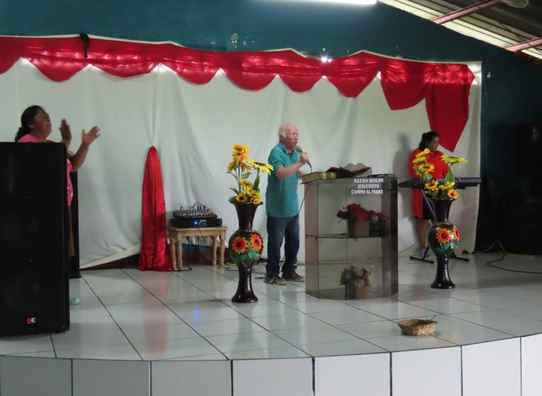 Pastor Esmerito Reyes stands behind a podium preaching to a congregation.