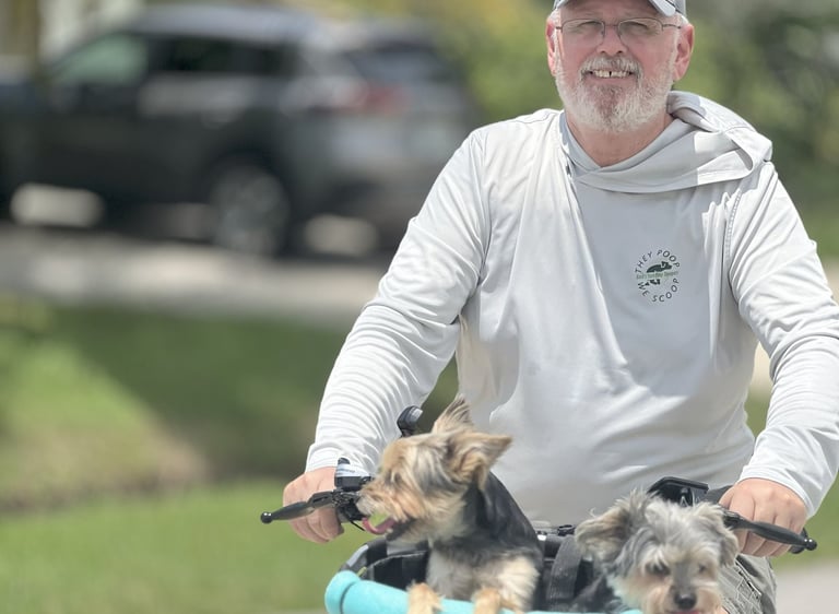 Robert smiling while riding a bicycle with two dogs in a basket