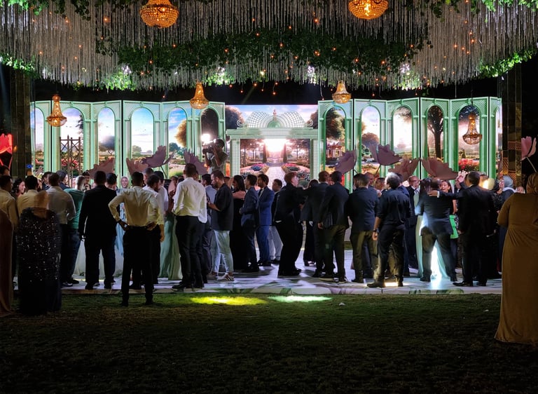 a group of people standing on a stage in front of wide led screen with garden scenery on it