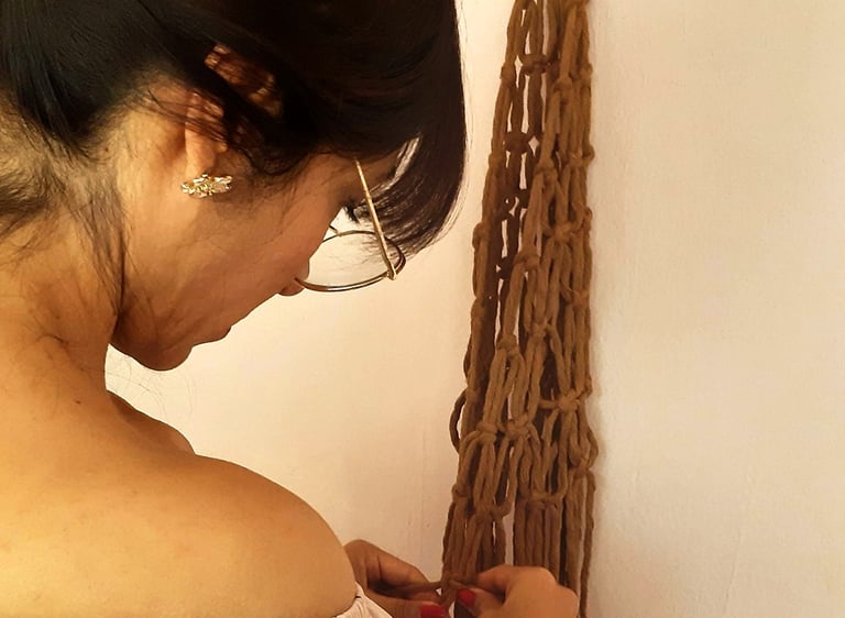 mujer haciendo un frutero de macrame en un taller, haciendo nudo por nudo.