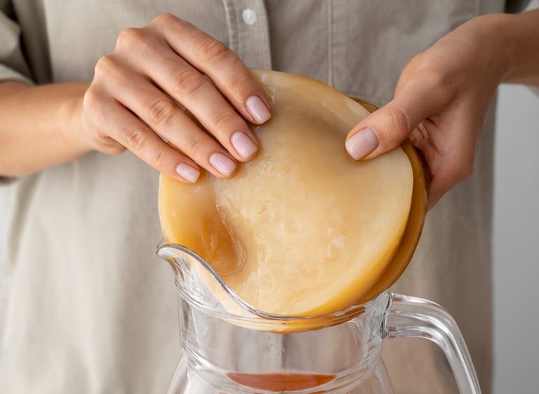 Una persona colocando un cultivo iniciador de SCOBY fresco en una jarra de vidrio.