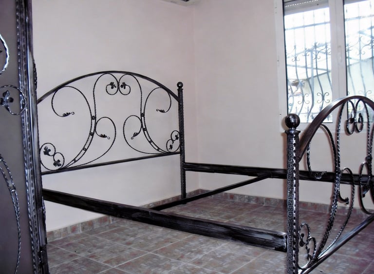 Elegant wrought iron bed frame with a decorative scrollwork headboard in a bedroom.