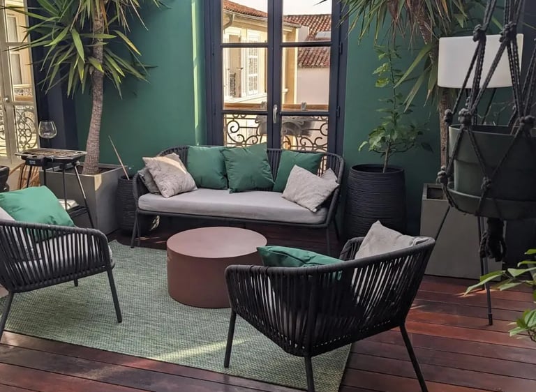 Aménagement d'une terrasse avec salon de jardin, terrasse bois rouge et mur vert décoratif. Harenova