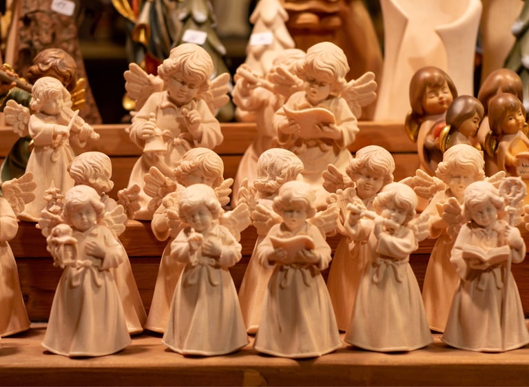 Handcrafted wooden angel figurines and musical cherub statues displayed at a traditional Christmas market.