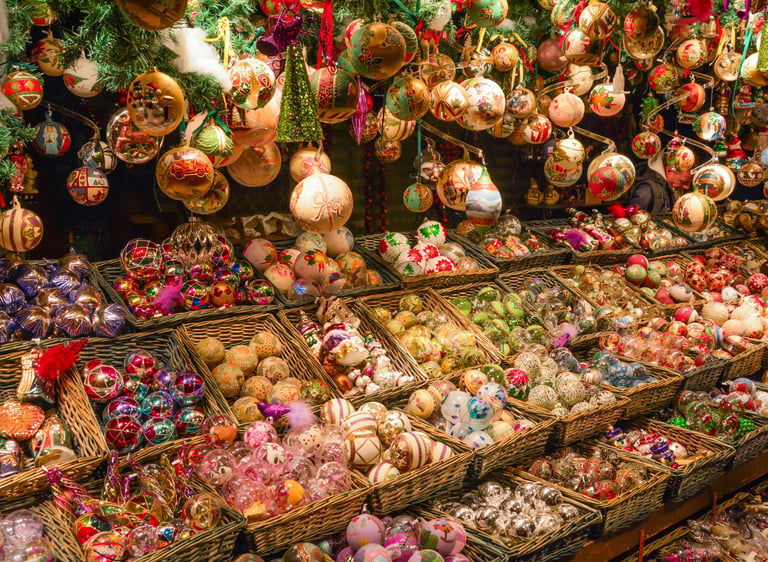 Hand-painted glass Christmas ornaments displayed in wicker baskets at a festive European holiday market.