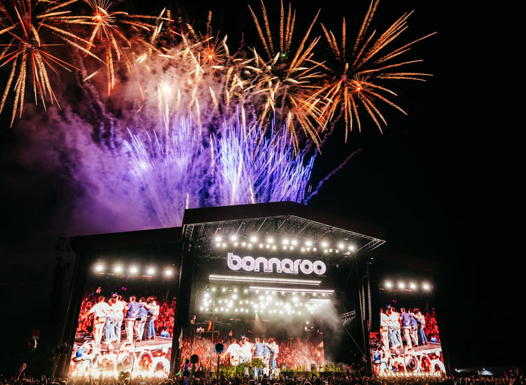Fireworks explode over the Bonnaroo music festival main stage at night during a live concert performance.