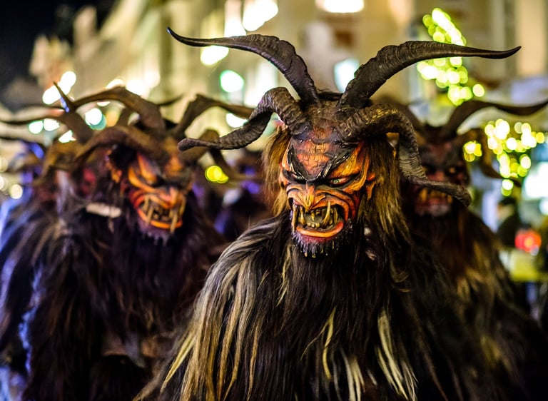 Traditional Krampus figures with terrifying masks and horns during a festive European winter parade.