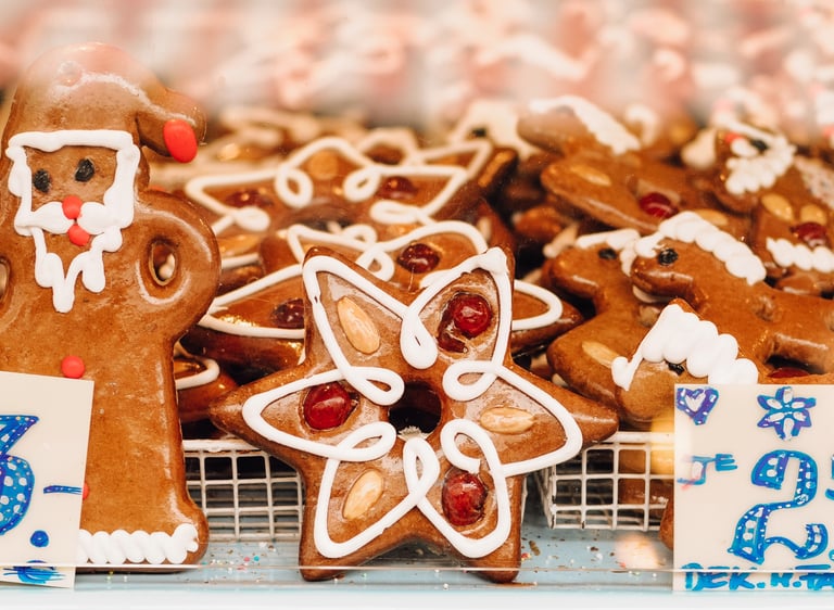 Decorated gingerbread cookies in Santa and star shapes at a European Christmas market stall.