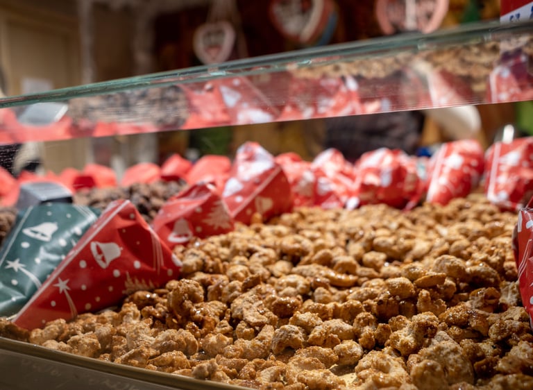 Roasted candied almonds and nuts displayed in festive paper cones at a traditional Christmas market stall.