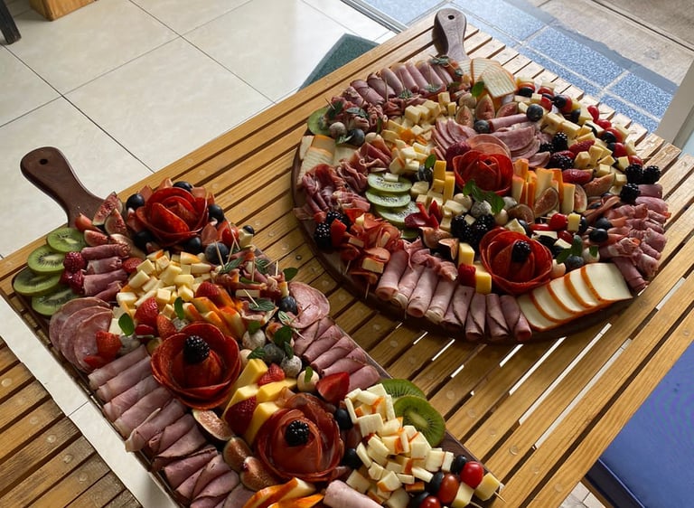 Two large charcuterie and cheese boards beautifully displayed on wooden trays.