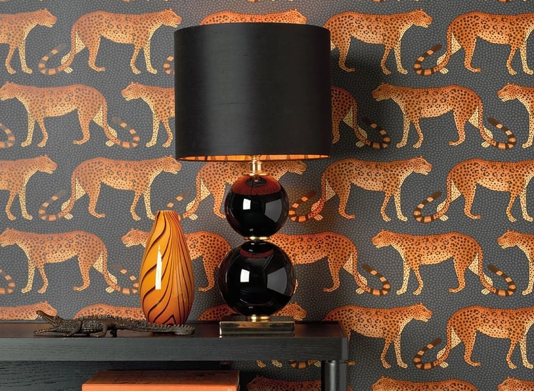 Modern interior featuring leopard print wallpaper with a black table lamp and stacked coffee table books.