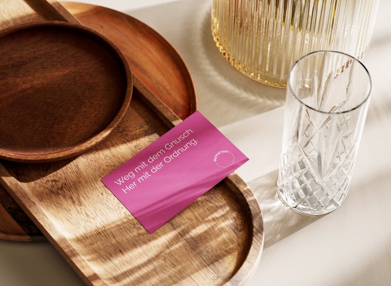 Magentafarbige Visitenkarte auf einem Holztablett.