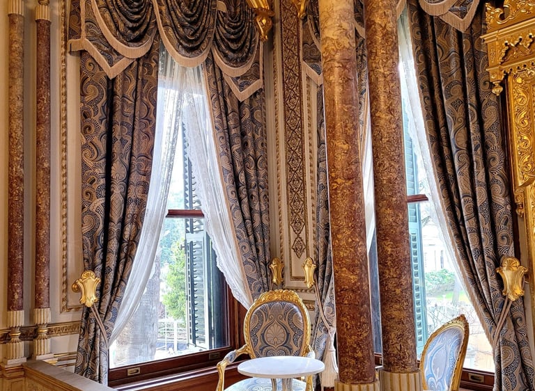 Opulent palace interior featuring marble columns, ornate gold trim, and luxurious blue damask curtains.