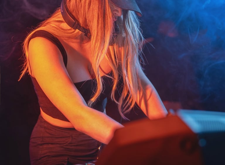 Kat Bendis wearing a black baseball cap mixing music on a DJ controller 