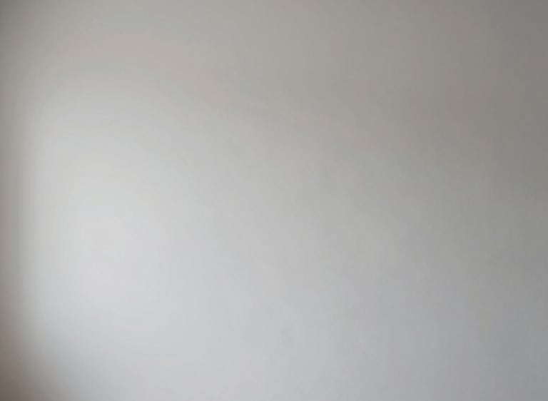Modern construction worker applying plaster on a wall in a bright, minimalist interior.