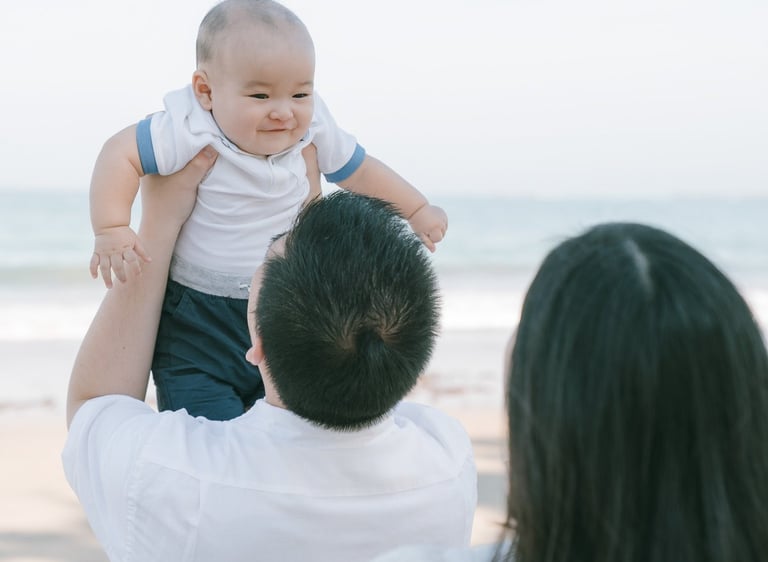 Parents lifting baby by the beach at Intercontinental Jimbaran captured in a joyful and candid family photography moment