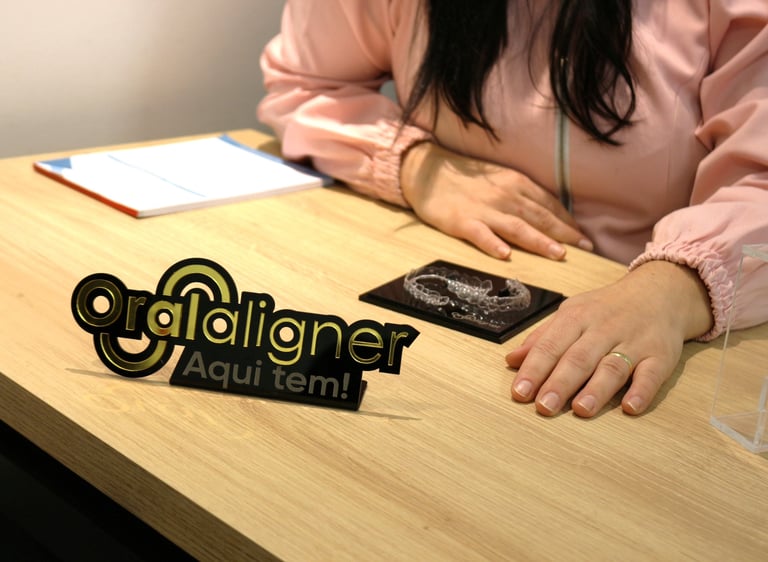 a woman sitting at a table with a invisible teeth aligner in front of her