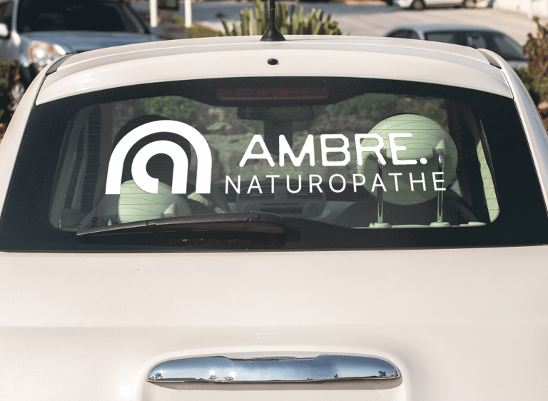 Décalcomanie blanc sur vitre arrière de voiture d'une naturopathe avec un logo professionnel.