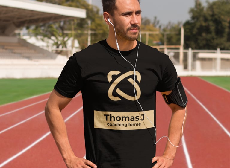 Homme en t-shirt noir avec un logo de coaching forme debout sur une piste de course rouge.