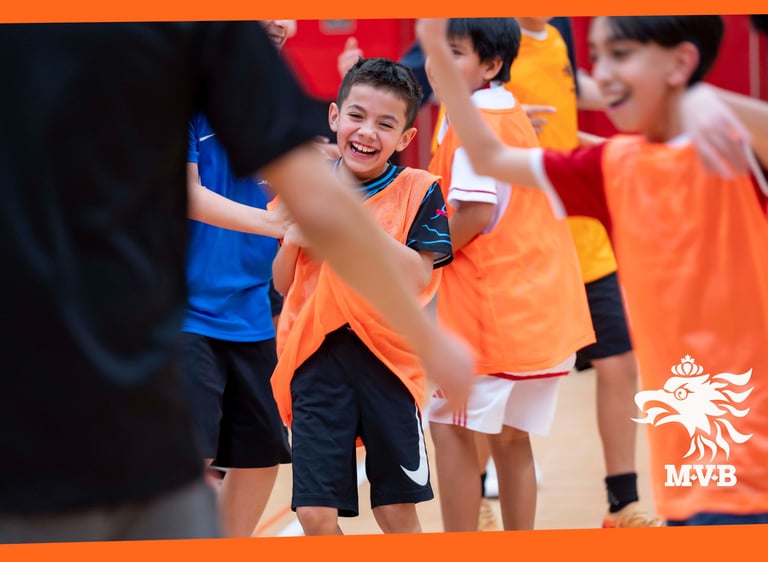 Smiling young MVB FC soccer student playing youth indoor soccer with teammates in Mississauga
