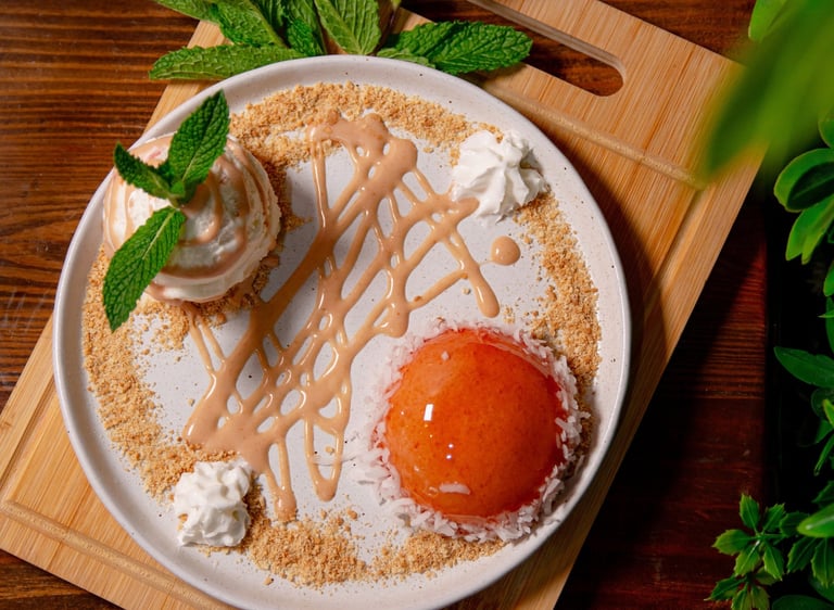 Gourmet peach dessert with fresh mint, crumble, and caramel drizzle on a wooden board.