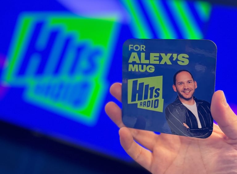 A Hits Radio drinks coaster that says 'for Alex's mug' on it.