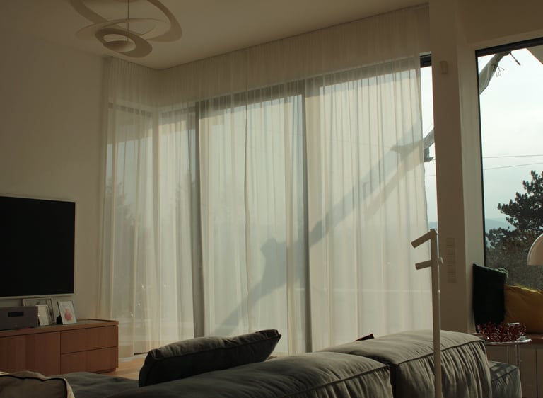 A big window hanged with wavy day curtains