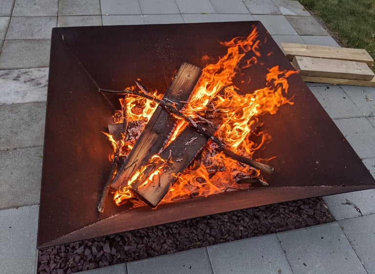 a square steel firepit with a large fire burning inside