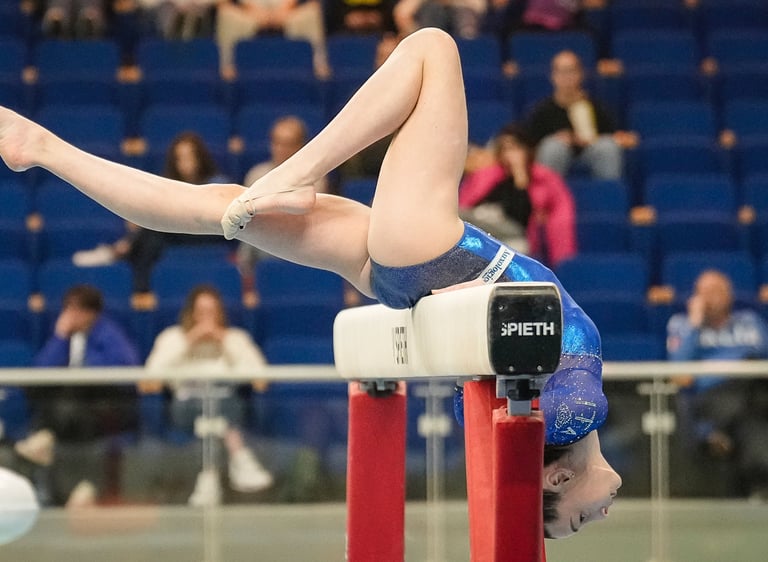 Gymnast performing a balancing routine on a balance beam during a gymnastics competition.
