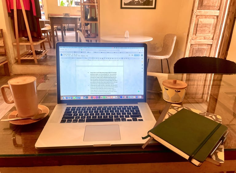 A laptop on a cafe table next to a latte and notebook, perfect for remote work or blogging.